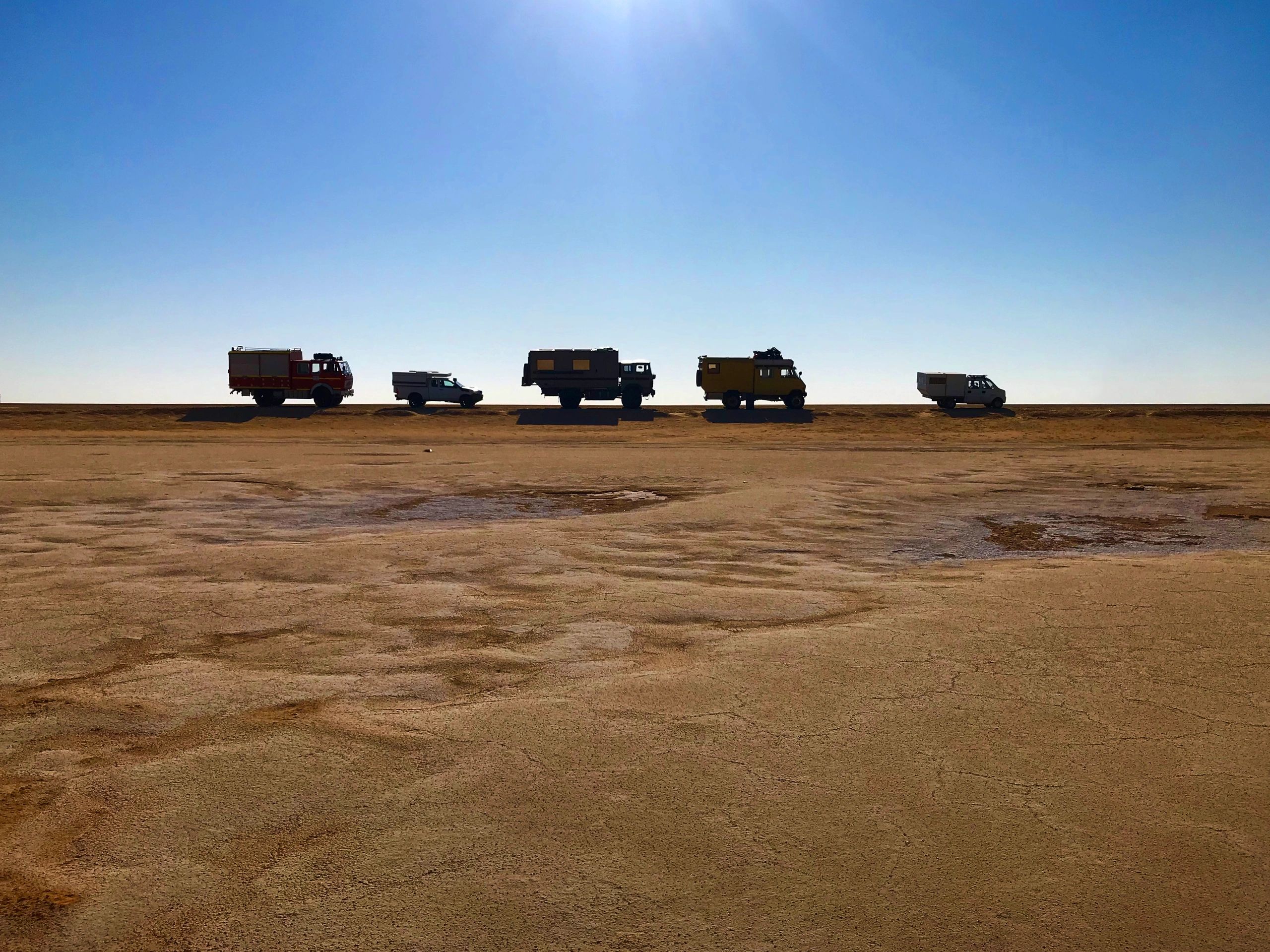 Off-road vehicles lined up under a blue sky