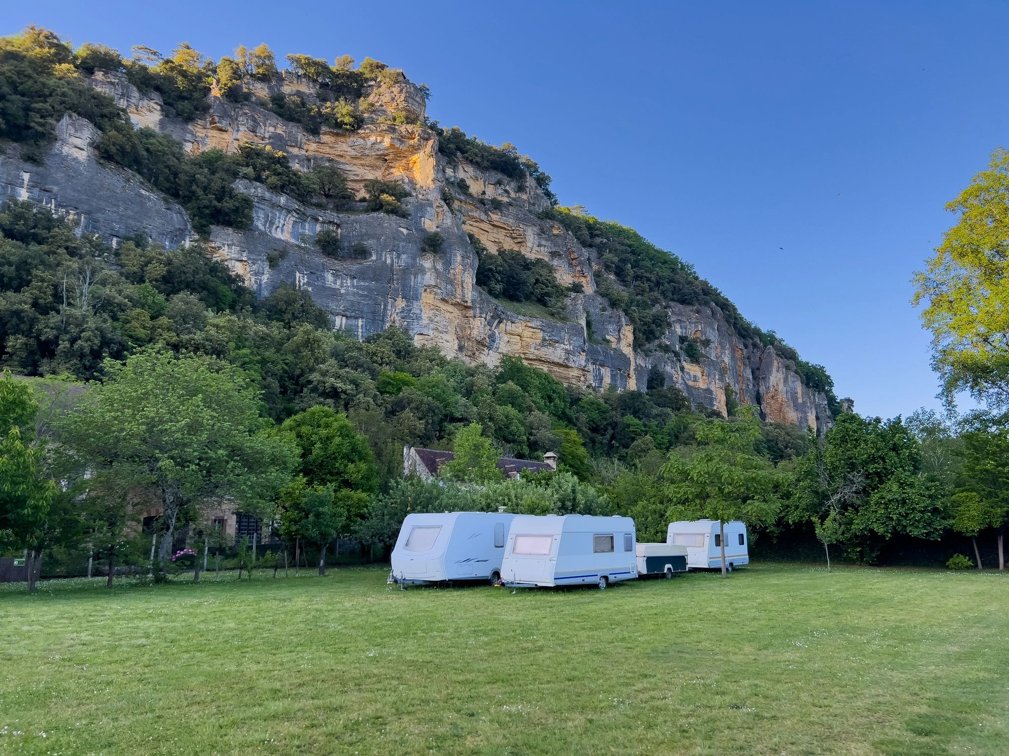 Campers parked on a meadow below a cliff
